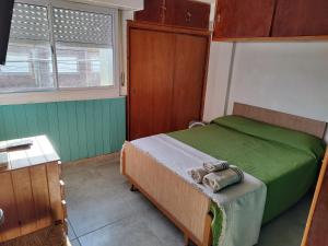 Dormitorio pequeño con cama con manta verde en A una cuadra de la playa con vista en San Clemente del Tuyú