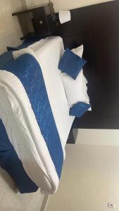un letto con cuscini bianchi e blu di شقق مساكن الراية المخدومه a Al Khobar