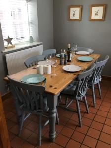 a wooden table with chairs and wine glasses on it at Beautiful mews cottage. Ledbury town centre. in Ledbury