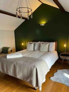 a bedroom with a large bed with a green wall at Beautiful mews cottage. Ledbury town centre. in Ledbury