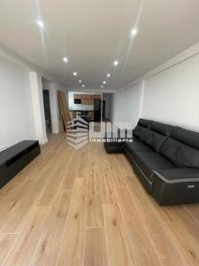 a living room with a black couch and a wooden floor at UIM Mediterraneo Conqueridor Wifi in Sagunto