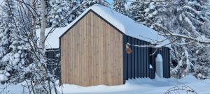 a woodenshed in the snow with snow covered trees at Level780 in Koszarawa
