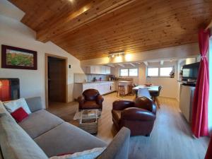 a living room with a couch and chairs and a kitchen at Chalet Relax in Pozza di Fassa