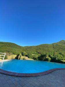 una piscina blu con una montagna sullo sfondo di Agriturismo Pompagnano a Pompagnano