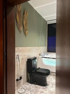 a bathroom with a black toilet and a tub at The Palms Resort (3) in Riyadh