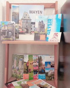 a book shelf with magazines and books on it at Mayen, Bäckerstr, Privatzimmer Nr4, Innenstadt, nähe Nürburgring & Burg Eltz, Gemeinschaftsbad in Mayen