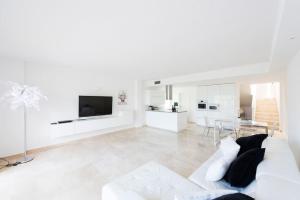 a white living room with a white couch and a tv at Luxusvilla Casaabel in Roca Llisa