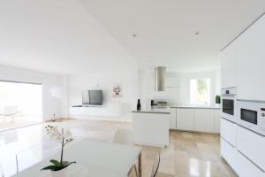 a white kitchen with a white table and a white counter top at Luxusvilla Casaabel in Roca Llisa