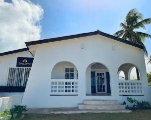 ein weißes Haus mit einer Palme im Hintergrund in der Unterkunft Puesta del Sol Guest House in San Andrés