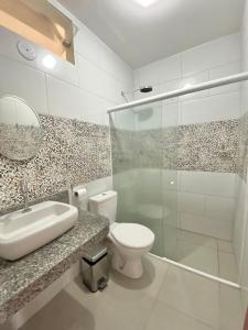 y baño con aseo, lavabo y ducha. en Flat por temporada, en São José da Coroa Grande
