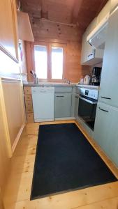 a kitchen with white appliances and a black rug at Ferienhaus Chalet Blockhaus Bayern in Stamsried