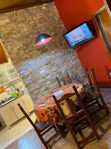 a dining room table with chairs and a tv on a brick wall at Bungalow Rio Olivia in Ushuaia