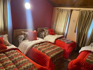 ウシュアイアにあるBungalow Rio Oliviaの赤い掛け布団付きのベッド3台が備わる部屋