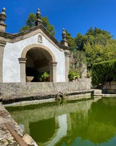 a stone archway over a pond in a garden at Quinta da Porta - Solar de Vale de Prazeres in Vale de Prazeres