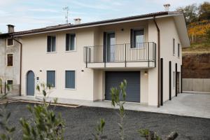 a house with a balcony and two garage doors at Affittacamere Casa Maria in San Giovanni Ilarione