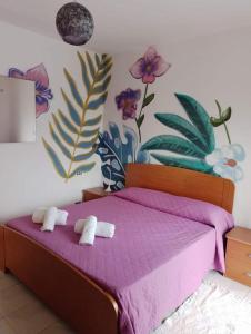 - une chambre avec un lit violet et des serviettes dans l'établissement B&B Romy House, à Pianopoli