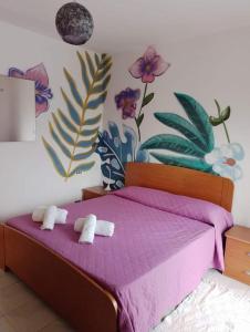 una camera da letto con un letto viola e asciugamani di Romy House a Pianopoli