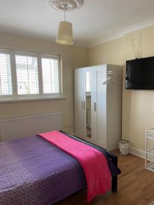 a bedroom with a purple bed and a tv at Streatham Common Bed & Breakfast in London
