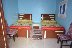 アスワンにあるGolden nubian guesthouseのベッド2台と椅子2脚が備わる客室です。