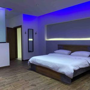 1 dormitorio con 1 cama grande y pared morada en The Palms Resort (2) en Riad