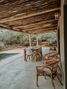 un patio con mesa y sillas bajo un techo de madera en UmnDeni Africa, en Hoedspruit