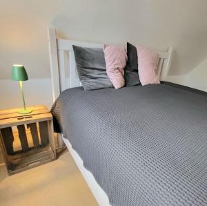a bedroom with a bed with pillows and a table at Die blaue Reetdachkate am Deich in Krummendeich