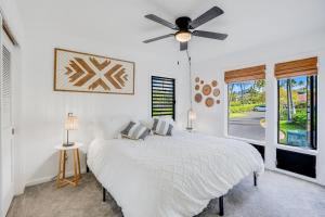 een witte slaapkamer met een bed en een plafondventilator bij Honu He'e Nalu - The Surfing Turtle - Ocean & Beachfront! Stunning Views! in Koloa