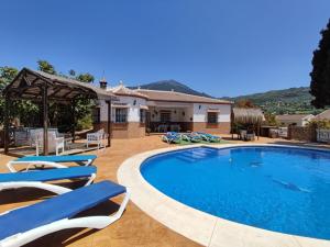 a swimming pool with chairs and a house at Los Naranjos in Alcaucín