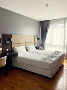 a bedroom with a large white bed and a desk at The Regent Bangtao Apartments in Bang Tao Beach