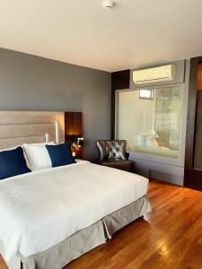 una camera con un grande letto bianco e una sedia di The Regent Bangtao Apartments a Bang Tao Beach