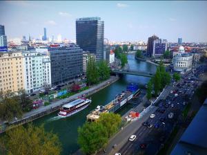a river with a boat in a city with cars at Vladys Vienna Apartments in Vienna