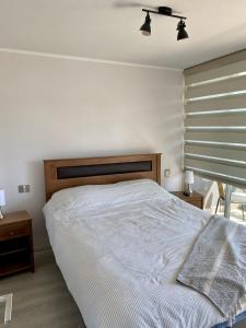 1 dormitorio con 1 cama con cabecero de madera y ventana en Costa de Montemar, en Concón