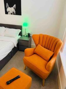an orange chair in a bedroom with a bed at Model 2bedrooms flat London. in Woolwich