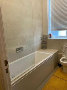 a white bathroom with a tub and a toilet at Model 2bedrooms flat London. in Woolwich