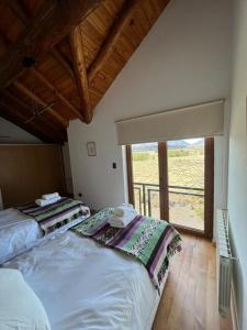 two beds in a room with a large window at Frontera Andina in Caviahue