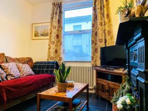 a living room with a couch and a tv at Cute Cottage 5 min walk from Cafés Station and Sea in Hastings