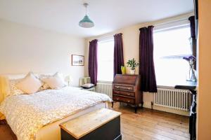 1 dormitorio con 1 cama, vestidor y ventanas en Cute Cottage 5 min walk from Cafés Station and Sea, en Hastings