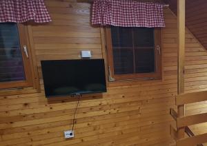 a television on a wall with two windows at Brunarica 6A - Smučišče Trije Kralji in Oplotnica