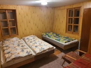 two beds in a room with wooden walls at Chata Božena - Čertovica in Jarabá