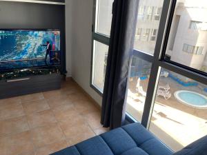 een woonkamer met een blauwe bank en een flatscreen-tv bij MARTSARAs PISCINA SARDINA in Gáldar