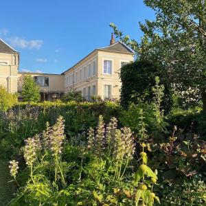 Un jardín con flores delante de un edificio. en Au Jardin des Deux Ponts, en Abbeville