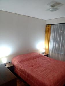 a bedroom with a red bed with two tables and two lamps at Hermoso departamento frente al casino in Viña del Mar