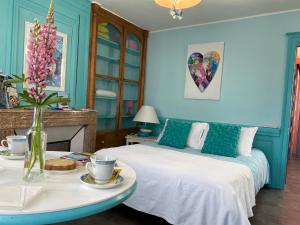 un dormitorio con 2 camas y una mesa con un jarrón de flores en Au Jardin des Deux Ponts, en Abbeville