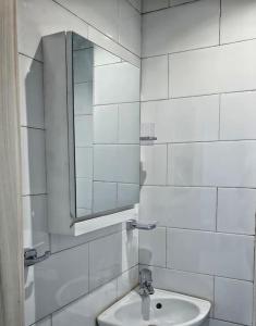 a white tiled bathroom with a sink and a mirror at The jewel of the coast in Sousse