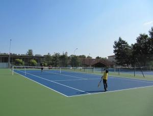 three people playing tennis on a tennis court at Hote du Lion in Saint-Genis-Pouilly