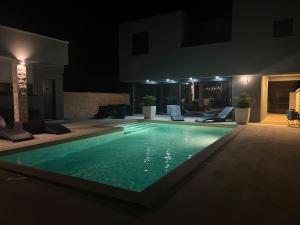 a swimming pool at night with chairs around it at Apartments Dream House Zaton in Zaton