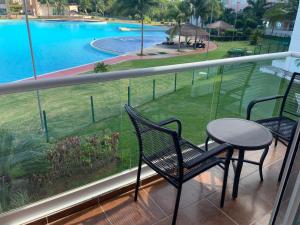 einen Balkon mit einem Tisch, Stühlen und einem Pool in der Unterkunft Departamento 'Hozanek' en Dream Lagoons Cancun in Cancún