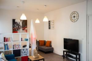 a living room with a tv and a couch and a clock at T1bis Wifi 25m2 Lumineux Elégant, Roubaix Centre in Roubaix