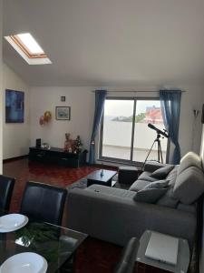 a living room with a couch and a large window at Penthouse Palmeira in Gaula