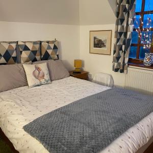 a bedroom with a bed with a gray comforter and a window at Carraholly in Liskeard